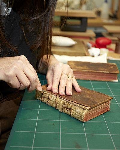 Une restauratrice répare un livre ancien à l’atelier des restauration
