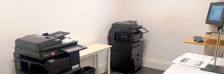 Espace de photocopies et impressions avec deux imprimantes noires et un ordinateur